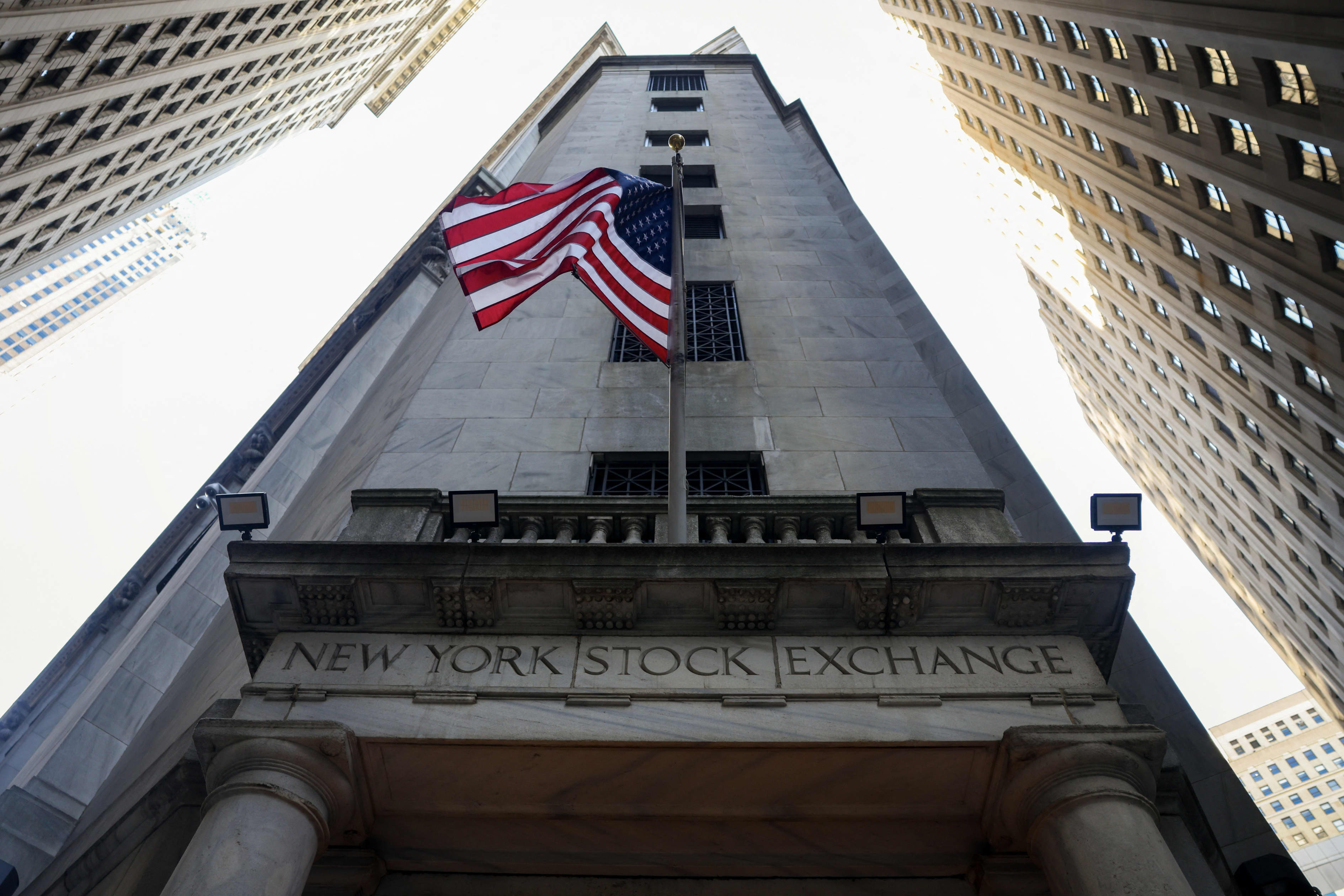 Exterior view of the New York Stock Exchange building with an American flag flying on its facade.