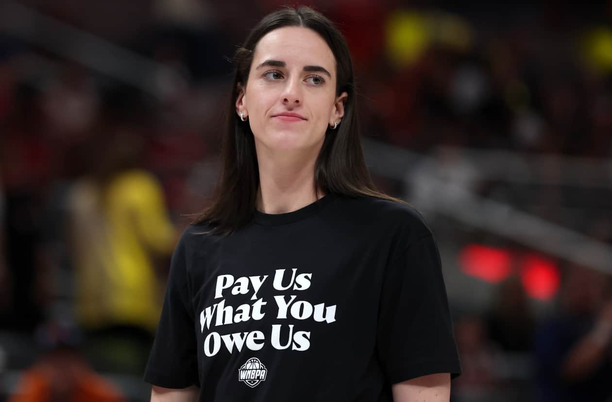 Caitlin Clark wearing a shirt that says "Pay Us What You Owe Us" at the WNBA All-Star Game.