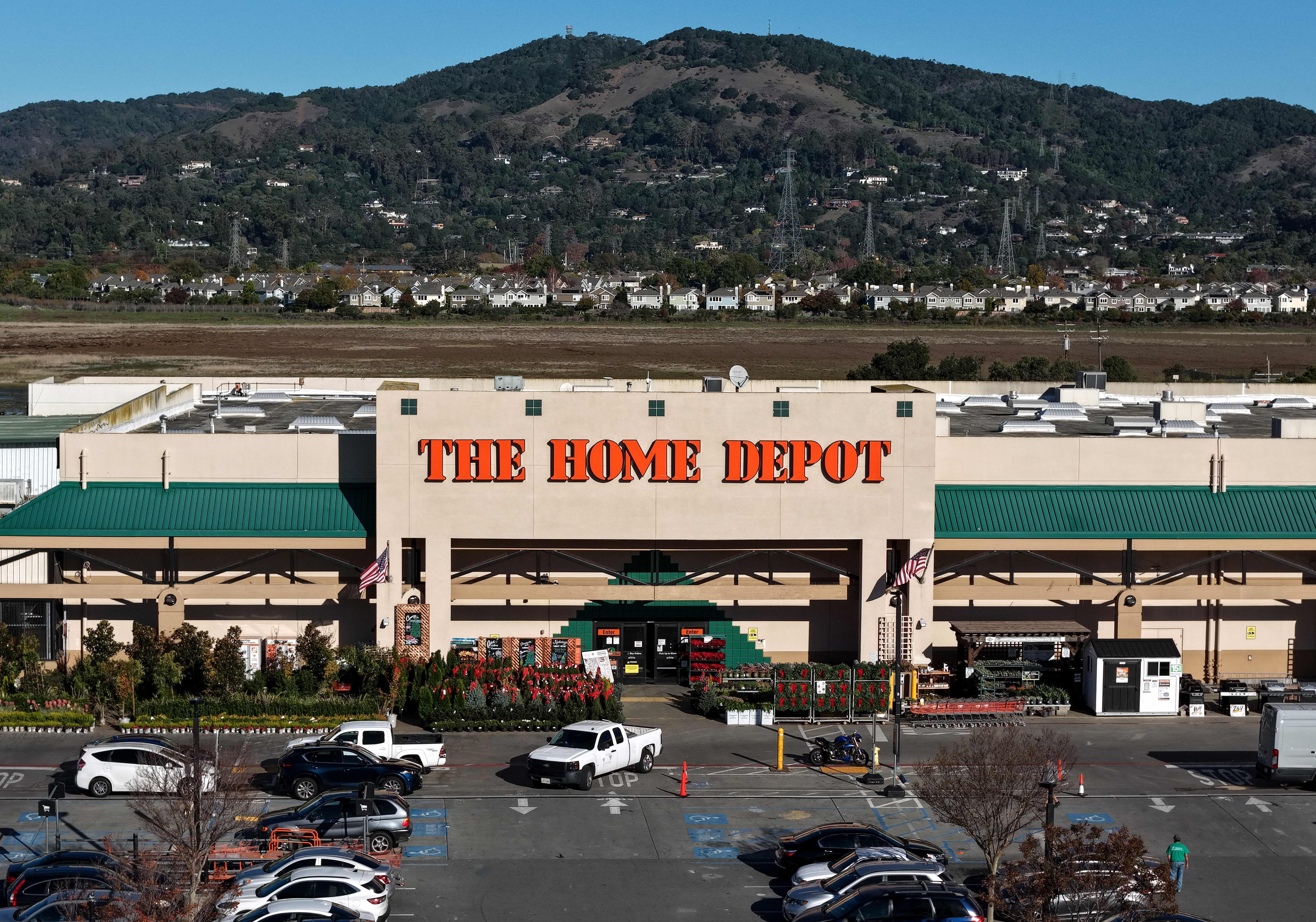Aerial view of a Home Depot store with a parking lot full of cars and a mountain in the background.