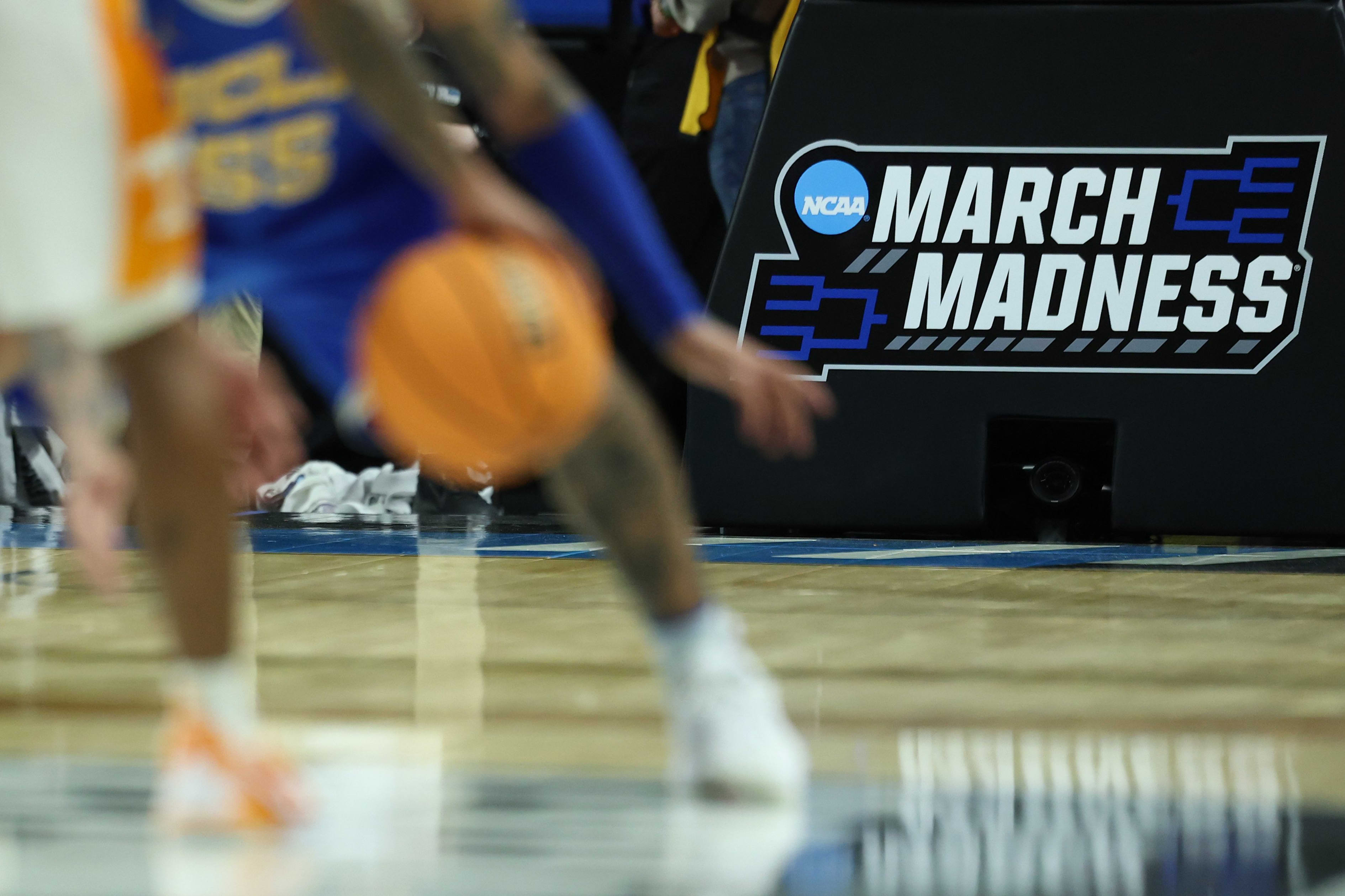 NCAA March Madness logo on a black sign at a basketball game.