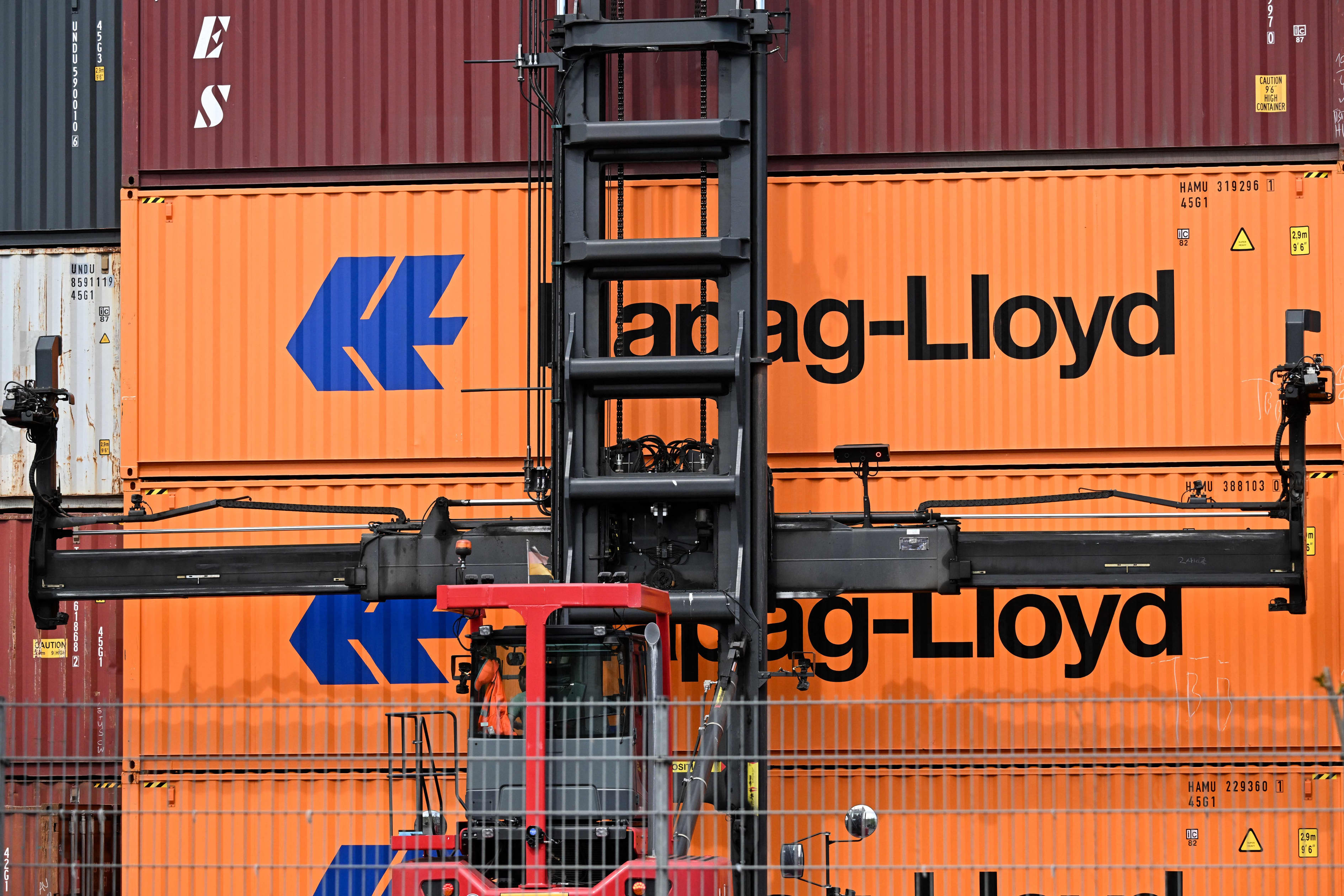 Forklift in front of stacked orange shipping containers from Hapag-Lloyd.