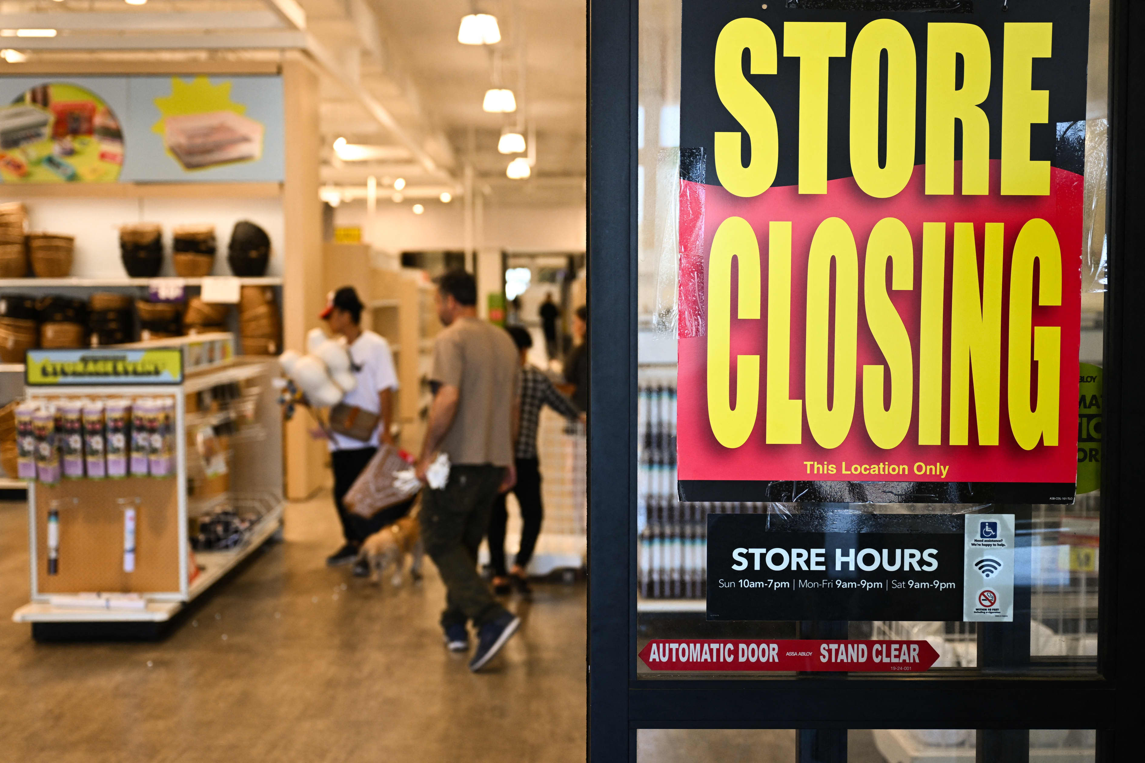 A store closing sign is displayed on the door of a JOANN Fabric and Crafts store as customers shop inside.