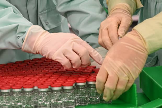 Laboratory technicians handle capped vials as part of filling and packaging tests for the large-scale production and supply of the University of Oxford's COVID-19 vaccine candidate at an Italian biologics manufacturing facility.