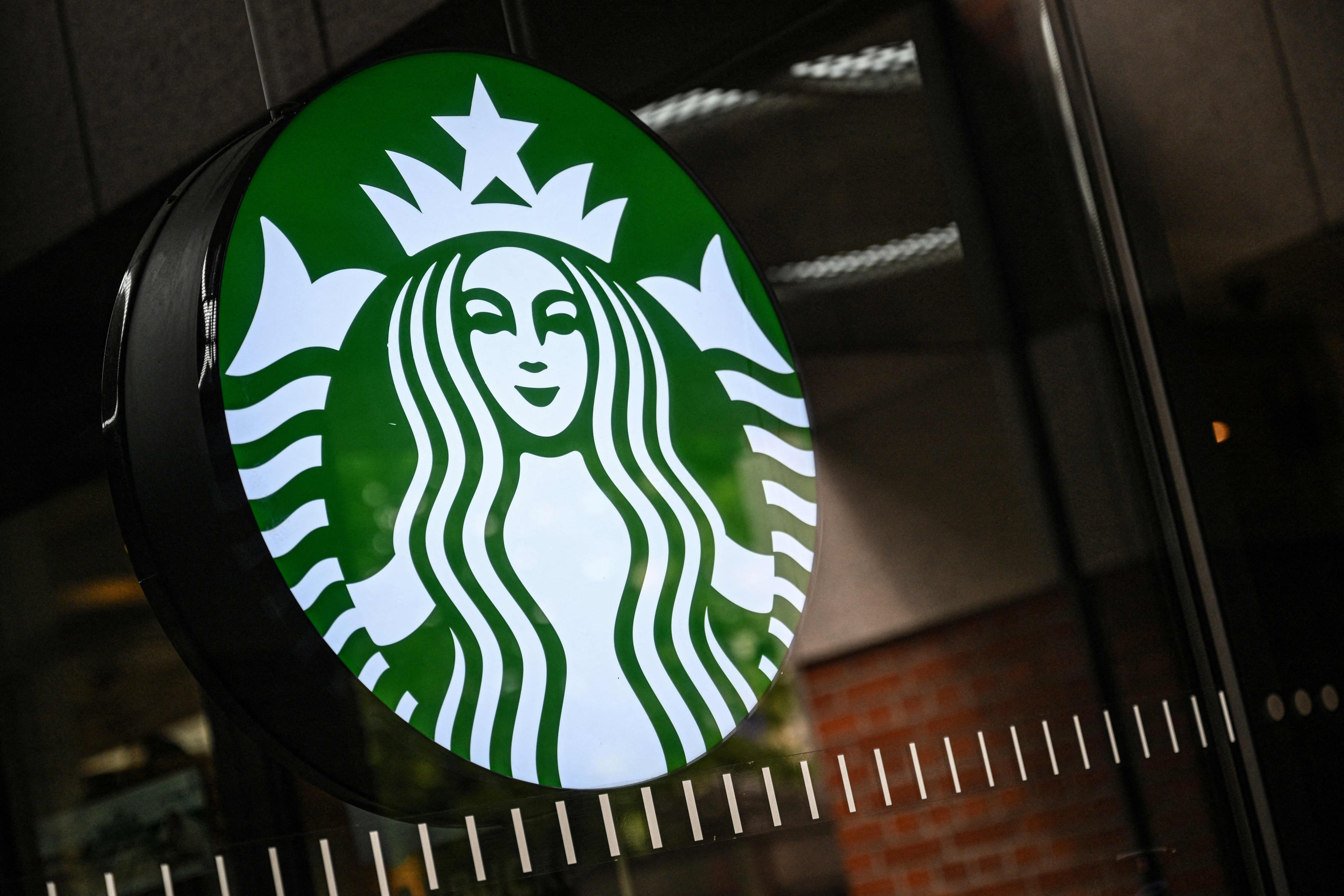 The illuminated Starbucks logo on a shop window.