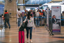 A passenger wears a face mask as she walks in the Kuala Lumpur International Airport (KLIA) in Sepang on November 29, 2021, as countries across the globe shut borders and renewed travel curbs in response to the spread of a new, heavily mutated Covid-19 coronavirus variation dubbed Omicron. (Photo by Mohd RASFAN / AFP) (Photo by MOHD RASFAN/AFP via Getty Images)