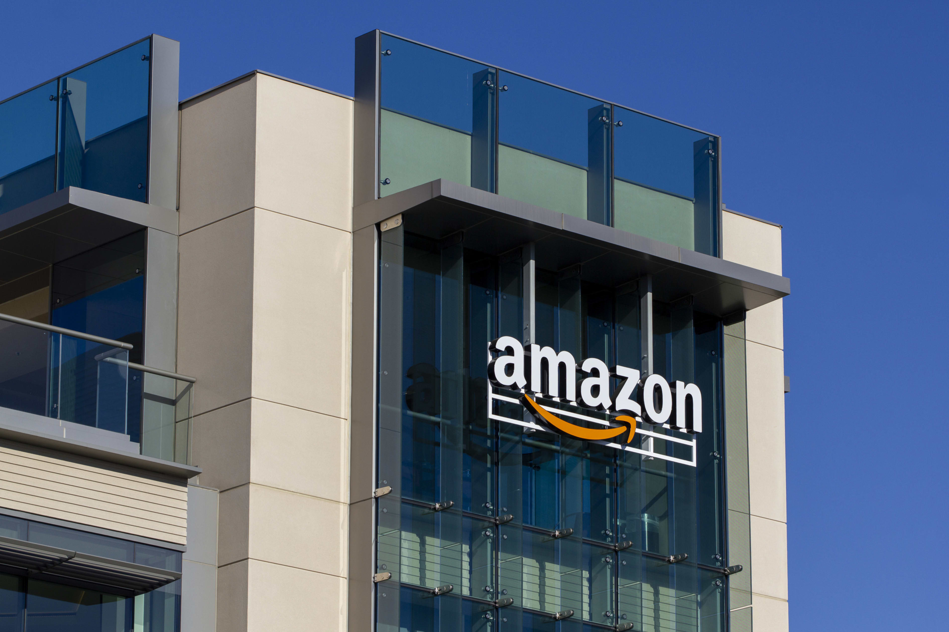 The Amazon logo is displayed on the side of a modern building with large glass windows.