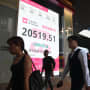 Pedestrians walk past a sign showing the numbers of the Hang Seng Index in Hong Kong on September 27, 2024. Hong Kong stocks soared more than three percent on September 27, capping its best week since the global financial crisis, fuelled by a series of Chinese measures this week aimed at kickstarting the economy. (Photo by Peter PARKS / AFP) (Photo by PETER PARKS/AFP via Getty Images)