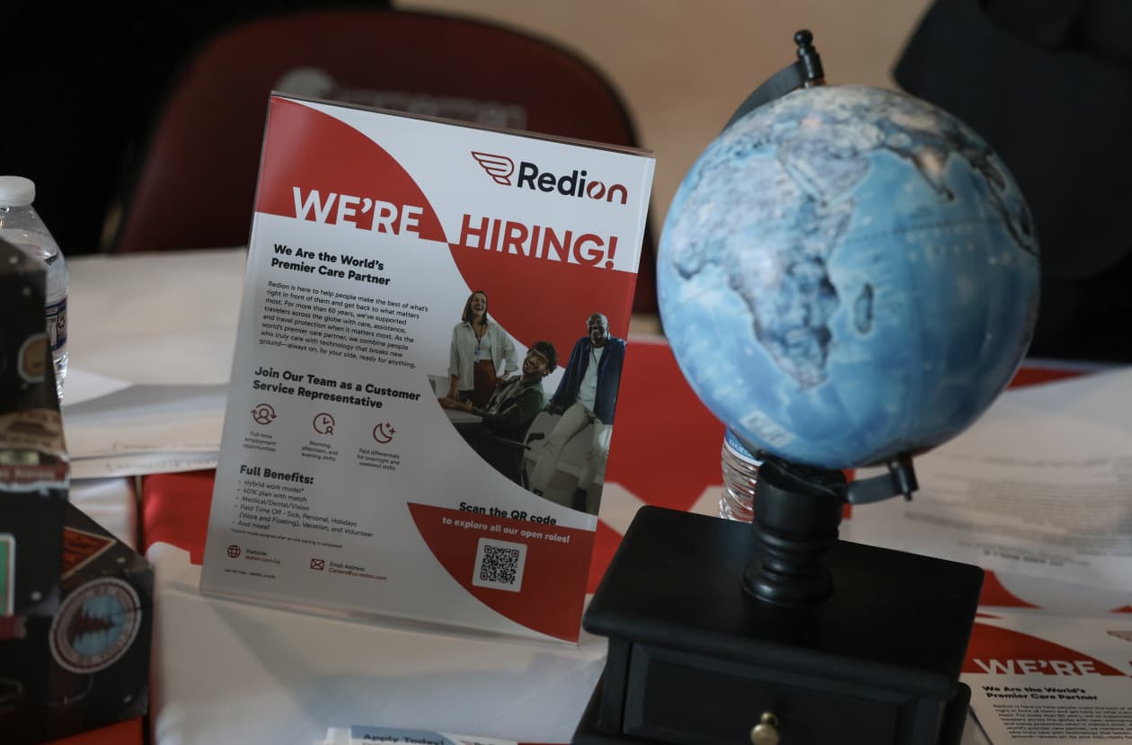 A "We're Hiring!" sign for Redion is displayed next to a small globe at a job fair.
