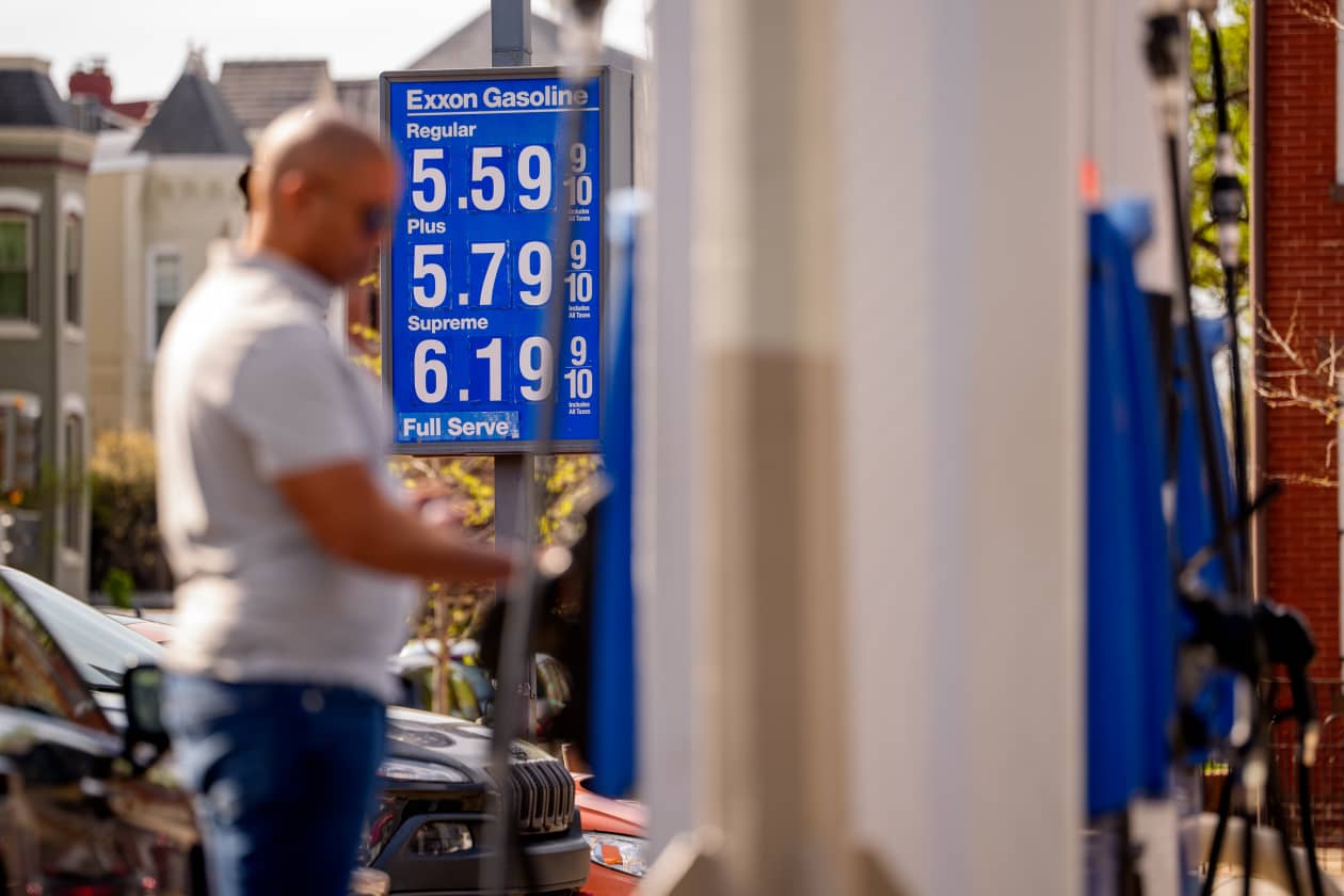 A person stands by a gas pump at an Exxon station where regular gas is $5.59 a gallon.