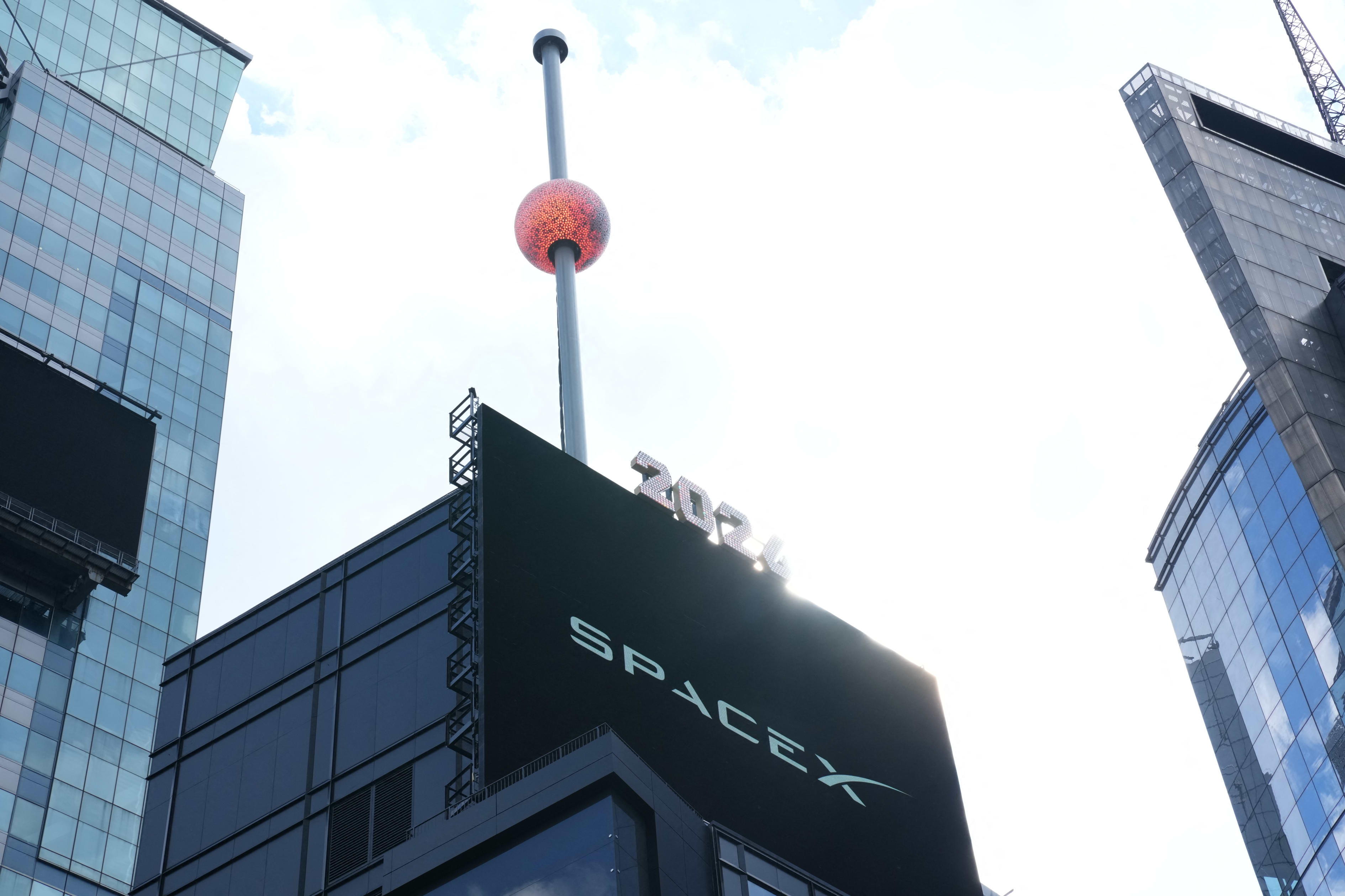The Times Square crystal ball above a billboard displaying "SPACEX" and "2024".