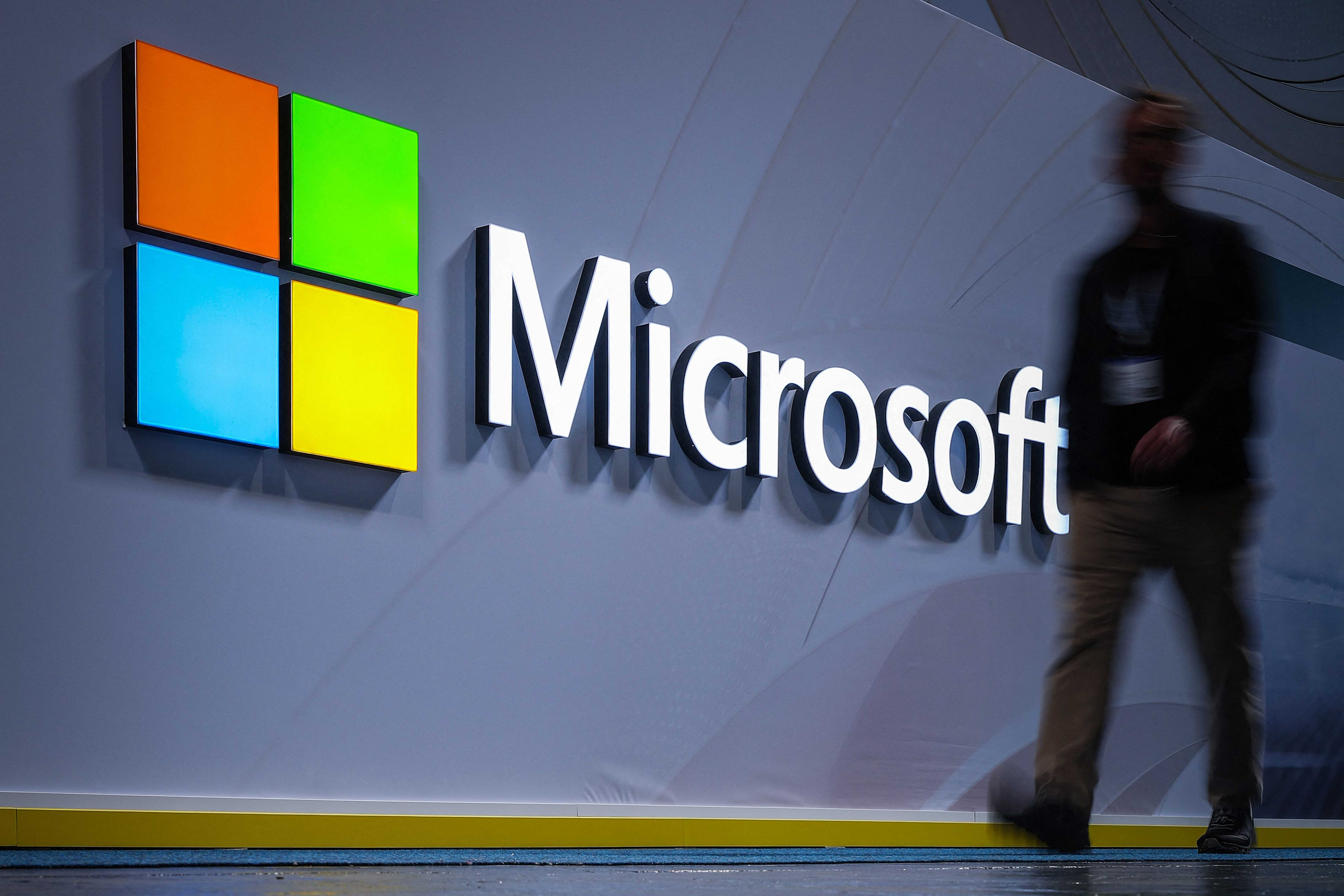 A visitor walks past a Microsoft logo at a trade fair.